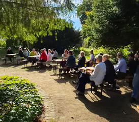 Mitarbeitenden sitzen beim Oktoberfest der Immanuel Klinik Märkische Schweiz bei strahlendem Sonnenschein im Park auf Bierbänken Mitarbeitenden sitzen beim Oktoberfest der Immanuel Klinik Märkische Schweiz bei strahlendem Sonnenschein im Park auf Bierbänken