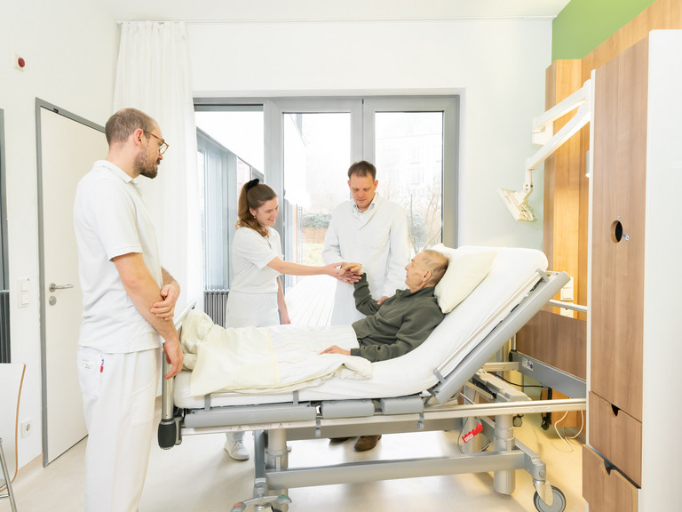 Ärzteteam stehen an einem Bett mit einem Patienten