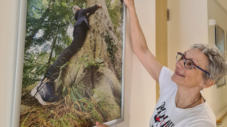 Frau hängt ein Bild im Flur des Diakonie Hospiz Wannsee auf Frau hängt ein Bild im Flur des Diakonie Hospiz Wannsee auf