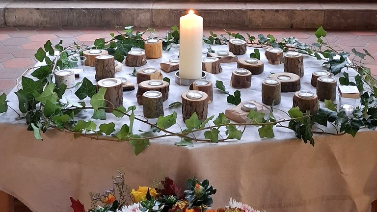 Kerzentisch der Gedenkfeier des Diakonie Hospiz Woltersdorf mit zentraler Kerze, Holz-Teelichtern und Efeukranz zum Gedenken an die verstorbenen Gäste Kerzentisch der Gedenkfeier des Diakonie Hospiz Woltersdorf mit zentraler Kerze, Holz-Teelichtern und Efeukranz zum Gedenken an die verstorbenen Gäste