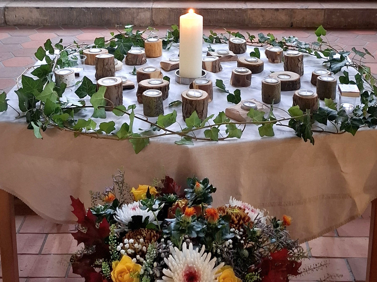 Kerzentisch der Gedenkfeier des Diakonie Hospiz Woltersdorf mit zentraler Kerze, Holz-Teelichtern und Efeukranz zum Gedenken an die verstorbenen Gäste Kerzentisch der Gedenkfeier des Diakonie Hospiz Woltersdorf mit zentraler Kerze, Holz-Teelichtern und Efeukranz zum Gedenken an die verstorbenen Gäste