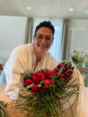 Eine ehrenamtlich engagierte Frau hält einen Strauß Blumen und blickt lächelnd in die Kamera im Diakonie Hospiz Woltersdorf.